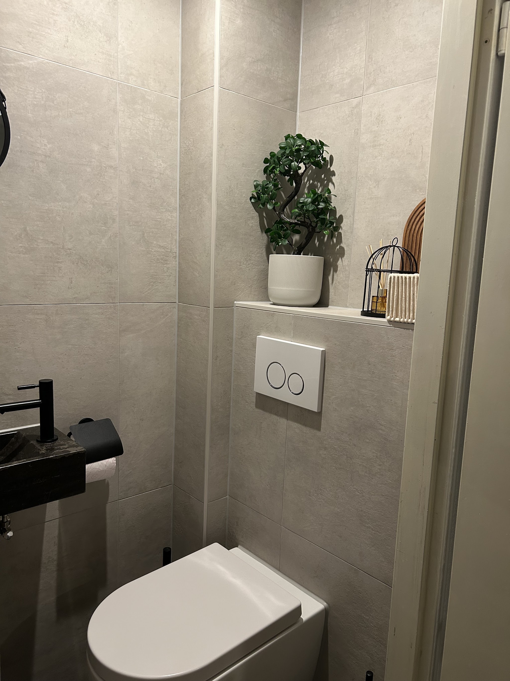 Toilet met hangend closet, grijze tegels en een betegelde plank